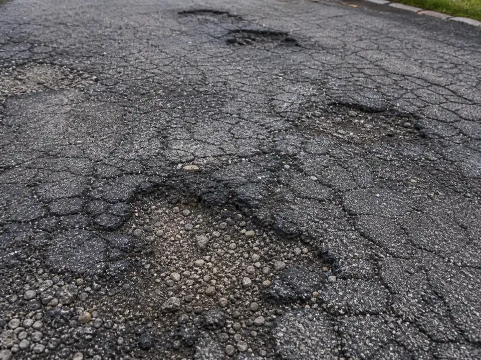 Widespread asphalt damage with potholes and alligator cracking