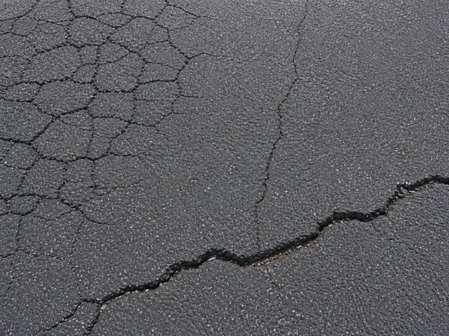 Close-up of block, hairline, and transverse cracks in asphalt
